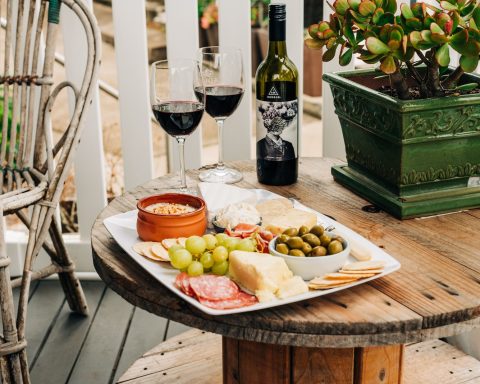 two wine glasses beside wine bottle on top of brown wooden reel table