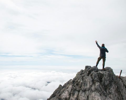 A man standing on top of a mountain with his arms in the air