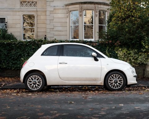 white 5 door hatchback parked beside brown concrete building during daytime