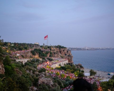A group of people standing on top of a hill next to the ocean