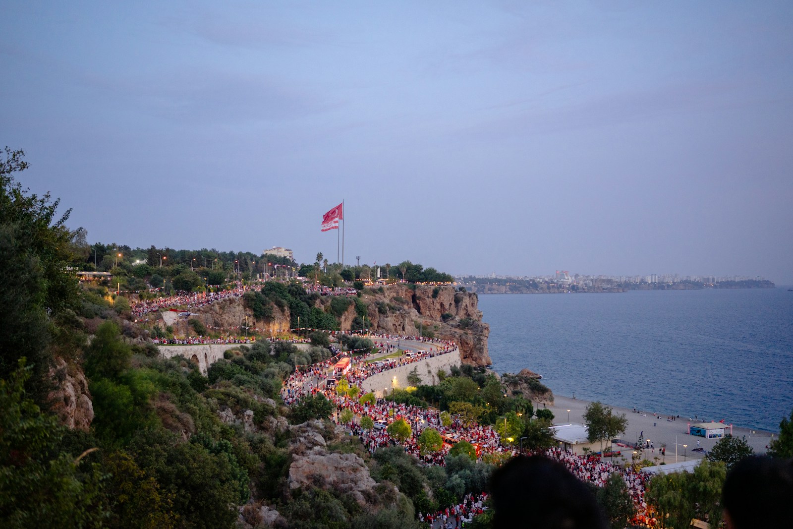 A group of people standing on top of a hill next to the ocean
