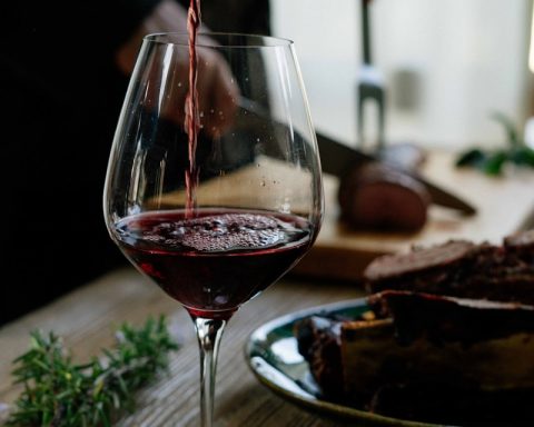 person pouring red wine on wine glass