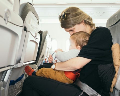 woman carrying baby while sitting on gray seat