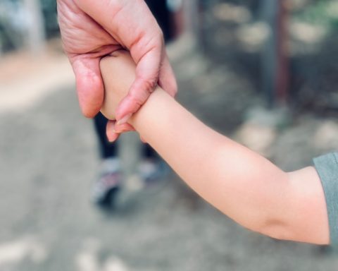 person in gray long sleeve shirt holding babys hand