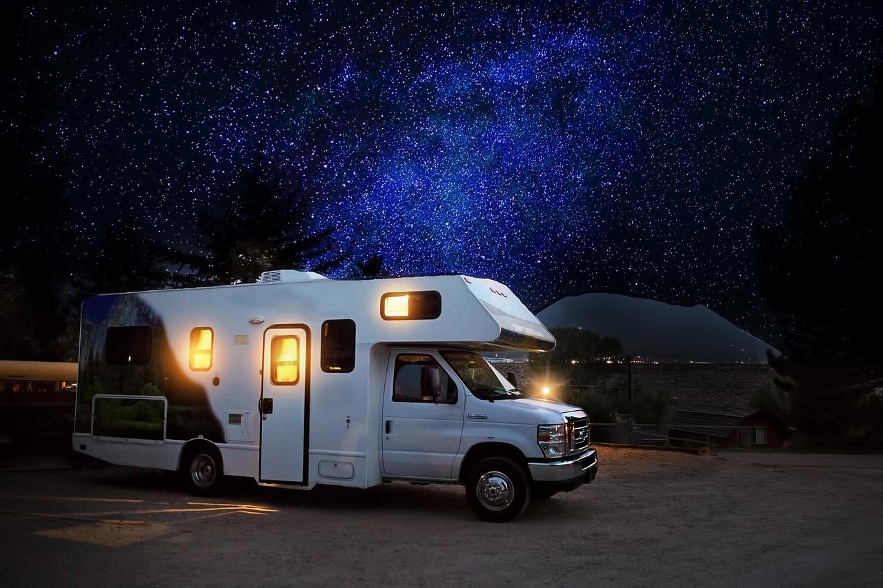 Glanzende zilveren Airstream caravan op een zonnige camping naast een groene weide